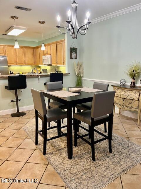 dining area featuring light tile patterned floors, a notable chandelier, visible vents, and crown molding