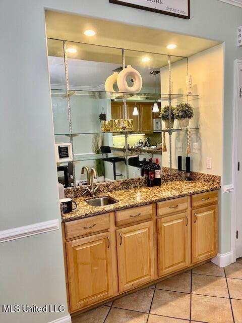 bar with light tile patterned flooring, a sink, and wet bar