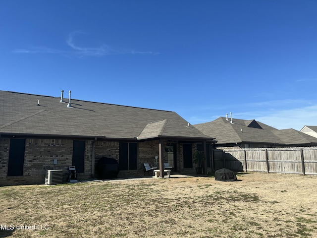 rear view of property featuring central air condition unit, a patio area, fence, and brick siding