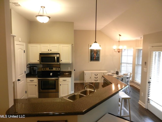 kitchen with stainless steel appliances, dark countertops, a sink, and white cabinets