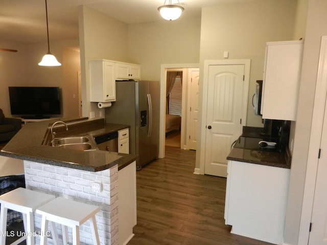 kitchen with white cabinets, dark countertops, a peninsula, stainless steel appliances, and a sink