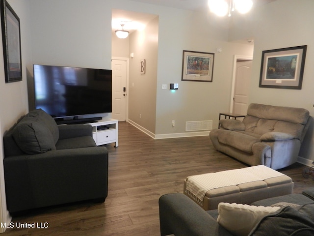 living area with baseboards, visible vents, and dark wood-type flooring