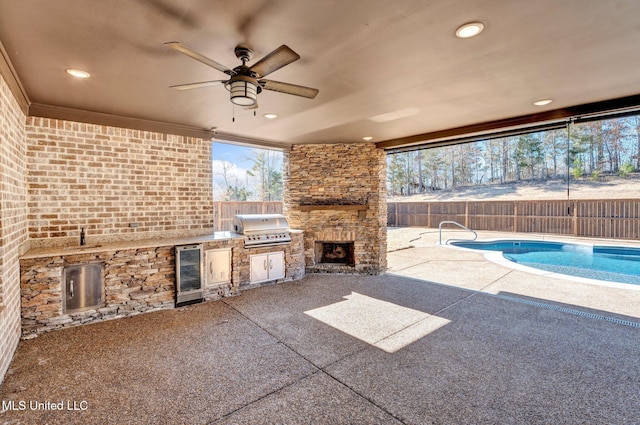 view of patio with an outdoor stone fireplace, area for grilling, an outdoor kitchen, a fenced in pool, and beverage cooler