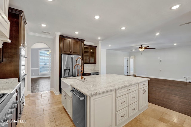 kitchen featuring sink, light stone countertops, a kitchen island with sink, ornamental molding, and stainless steel appliances