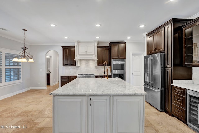 kitchen featuring crown molding, an island with sink, beverage cooler, and stainless steel appliances