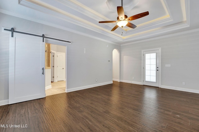 unfurnished room with crown molding, ceiling fan, a raised ceiling, dark wood-type flooring, and a barn door