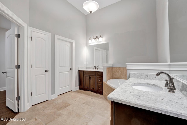 bathroom with a bath, vaulted ceiling, and vanity