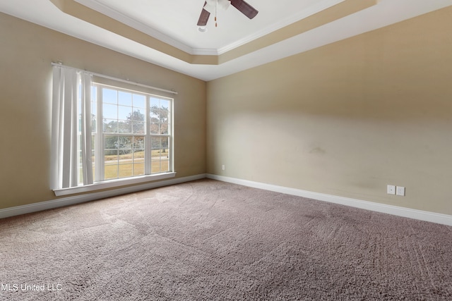 empty room featuring ornamental molding, ceiling fan, a tray ceiling, and carpet flooring