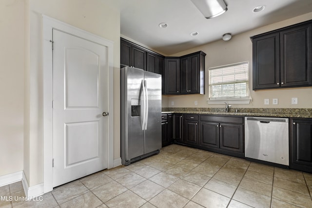 kitchen featuring sink, appliances with stainless steel finishes, light tile patterned floors, and dark stone countertops