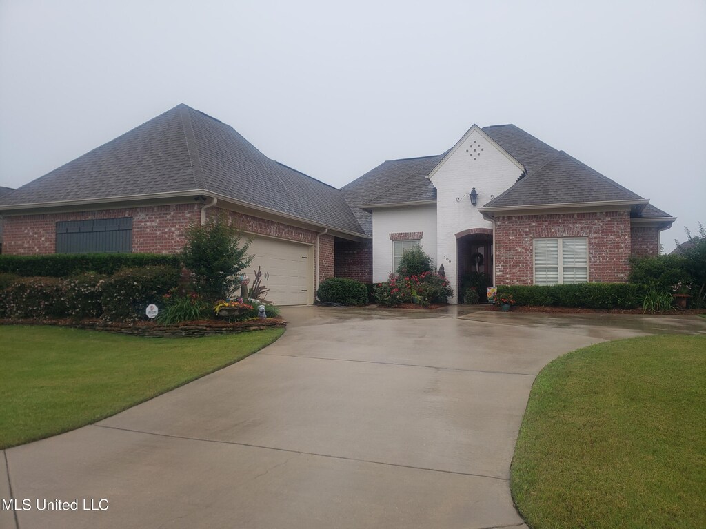 308 W Park St, Canton, MS 39046 - french provincial home featuring brick siding, roof with shingles, a front lawn, and driveway