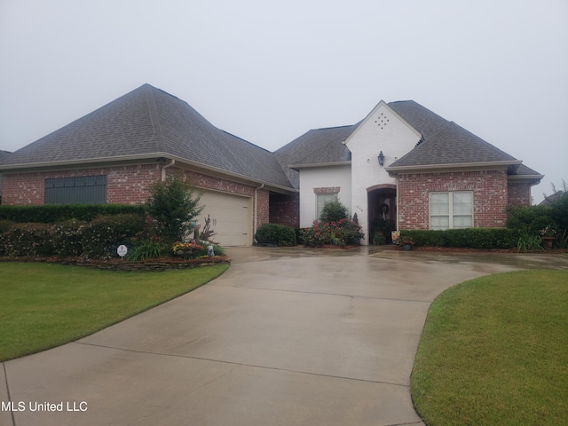 308 W Park St, Canton, MS 39046 - french provincial home featuring brick siding, roof with shingles, a front lawn, and driveway