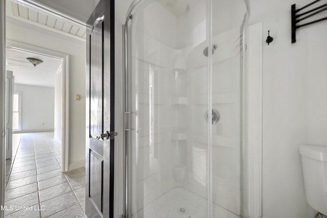 bathroom with toilet, a shower with door, tile patterned floors, and crown molding