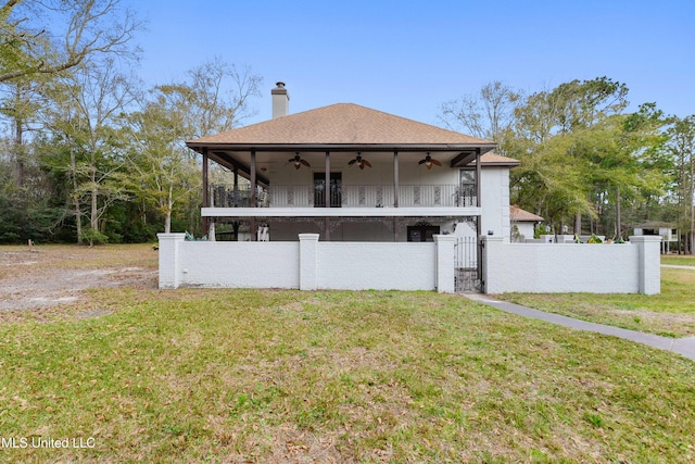 view of front facade featuring ceiling fan, a front lawn, and a balcony