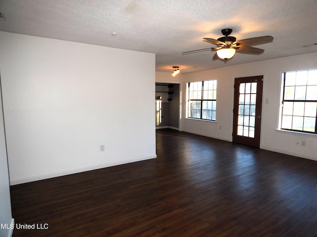 empty room featuring ceiling fan, dark wood-type flooring, and a textured ceiling