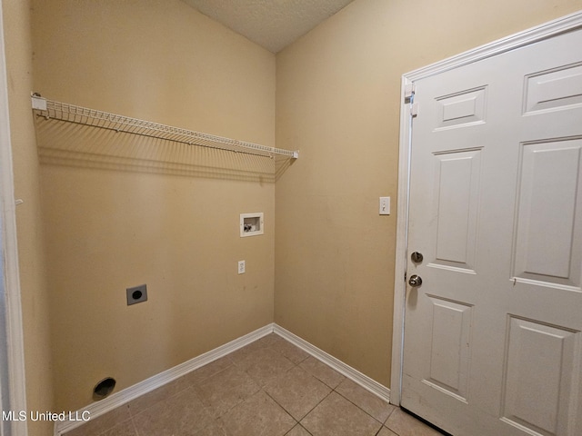 clothes washing area featuring electric dryer hookup, hookup for a washing machine, light tile patterned floors, and a textured ceiling