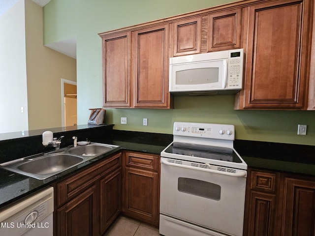 kitchen featuring white appliances, sink, light tile patterned floors, and dark stone counters