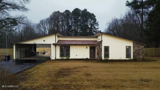 rear view of house featuring a carport and a lawn