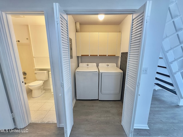 washroom featuring cabinet space, washing machine and clothes dryer, and wood finished floors