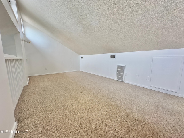 bonus room with lofted ceiling, visible vents, a textured ceiling, and carpet flooring