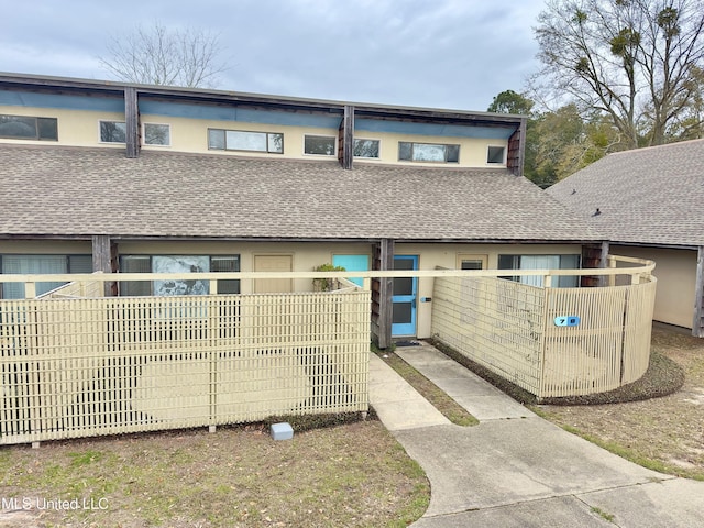 multi unit property with a shingled roof and stucco siding