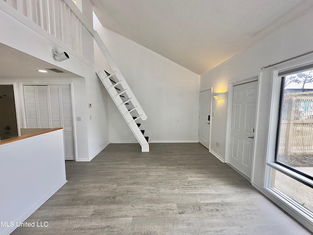 entryway featuring a textured ceiling, stairway, baseboards, and wood finished floors