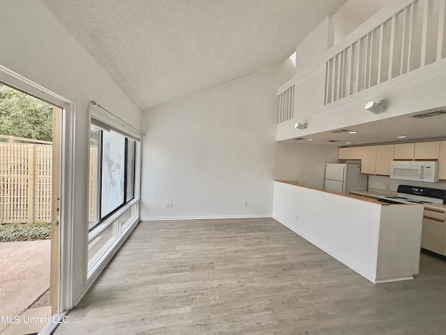 kitchen with white appliances, baseboards, light wood-style flooring, a textured ceiling, and high vaulted ceiling