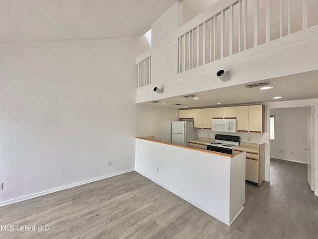 kitchen with light countertops, visible vents, wood finished floors, white appliances, and baseboards