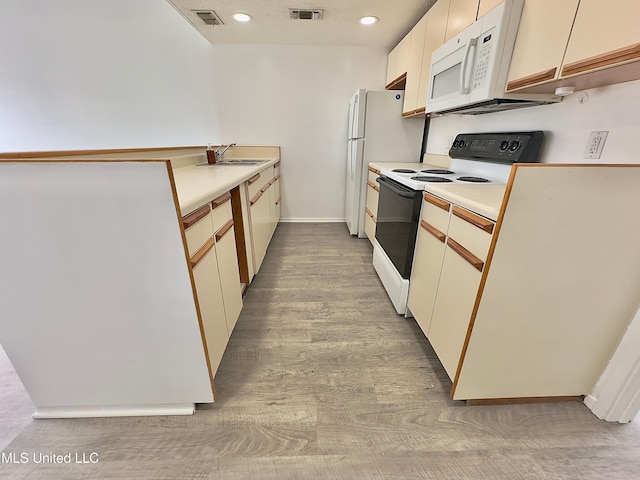 kitchen featuring white microwave, visible vents, range with electric cooktop, and light countertops