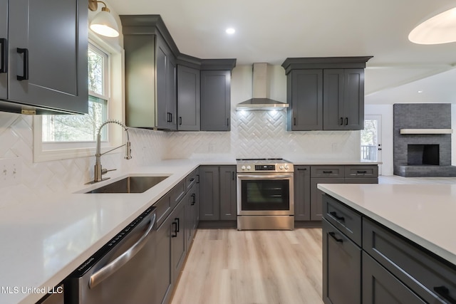 kitchen featuring a sink, light countertops, wall chimney exhaust hood, and stainless steel appliances