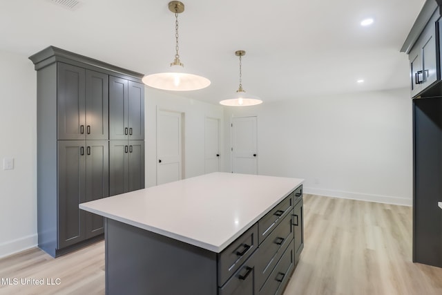 kitchen with gray cabinets, a kitchen island, light wood-style floors, light countertops, and hanging light fixtures