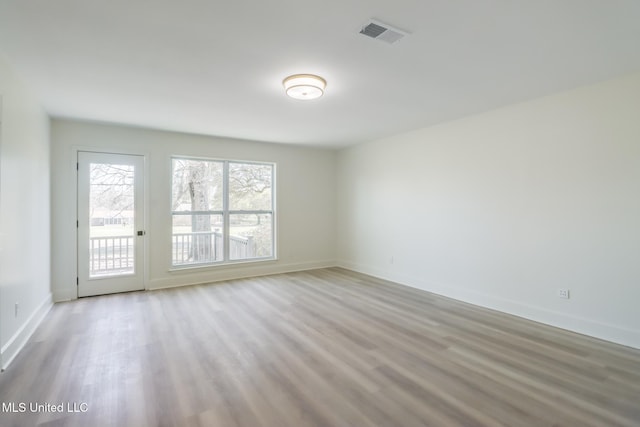 spare room with visible vents, baseboards, and wood finished floors