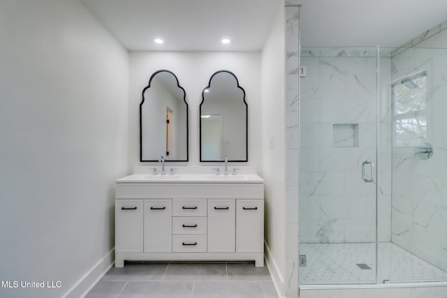 bathroom with double vanity, baseboards, a marble finish shower, and a sink