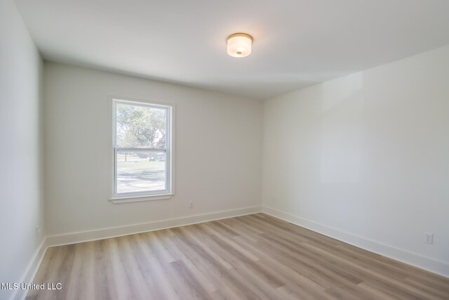 unfurnished room with baseboards and light wood-style flooring