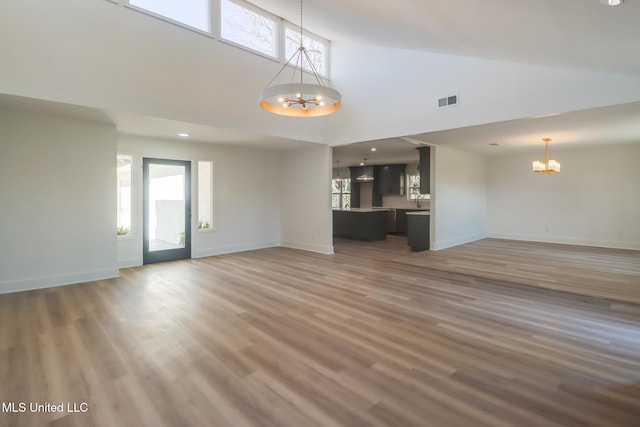 unfurnished living room featuring visible vents, a wealth of natural light, and a chandelier