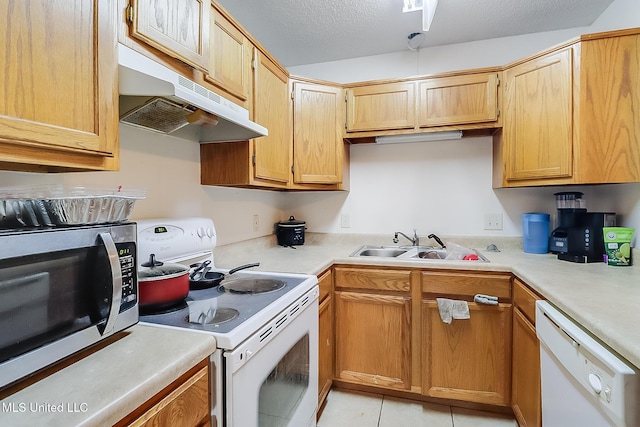 kitchen featuring light tile patterned floors, sink, white appliances, and a textured ceiling