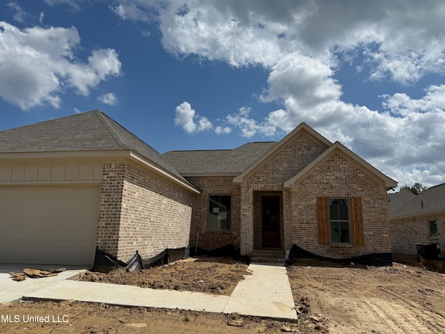 409 Butternut Dr, Canton, MS 39046 - view of front of property with brick siding, central AC unit, an attached garage, and a shingled roof