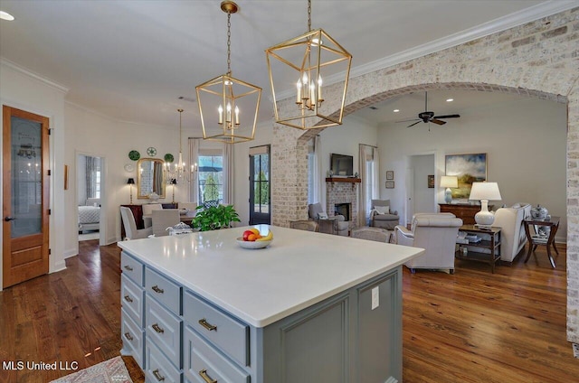 kitchen featuring gray cabinetry, open floor plan, arched walkways, a brick fireplace, and dark wood-style flooring