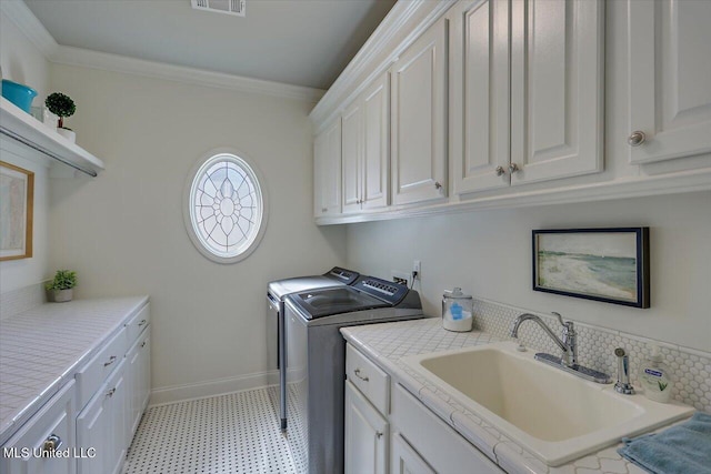 laundry room with washing machine and clothes dryer, crown molding, baseboards, cabinet space, and a sink