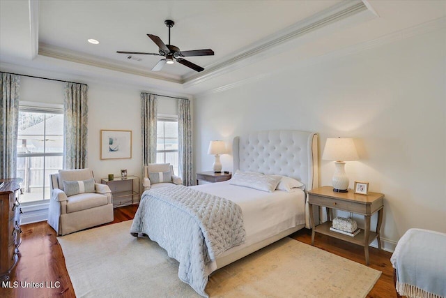 bedroom featuring visible vents, ornamental molding, a tray ceiling, and wood finished floors