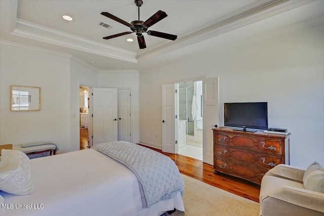 bedroom featuring visible vents, a tray ceiling, ornamental molding, recessed lighting, and wood finished floors