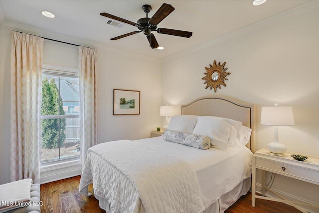 bedroom with multiple windows, wood finished floors, visible vents, and ornamental molding