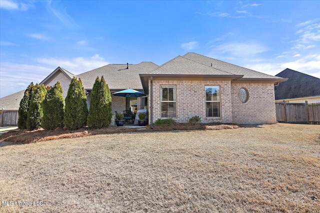 back of property featuring a patio, brick siding, roof with shingles, and fence