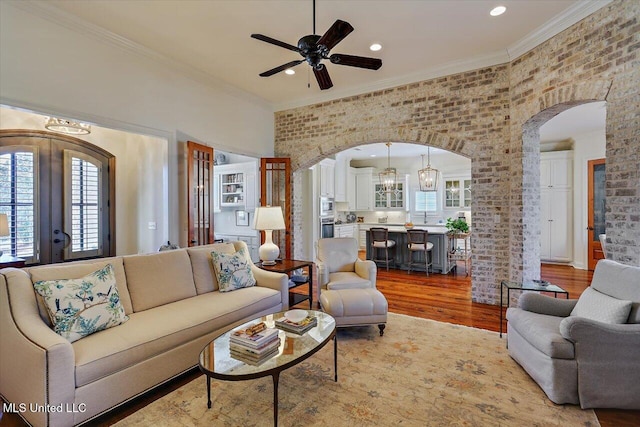 living room featuring arched walkways, ornamental molding, french doors, and wood finished floors