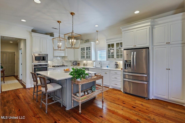 kitchen with decorative backsplash, white cabinets, appliances with stainless steel finishes, and a sink