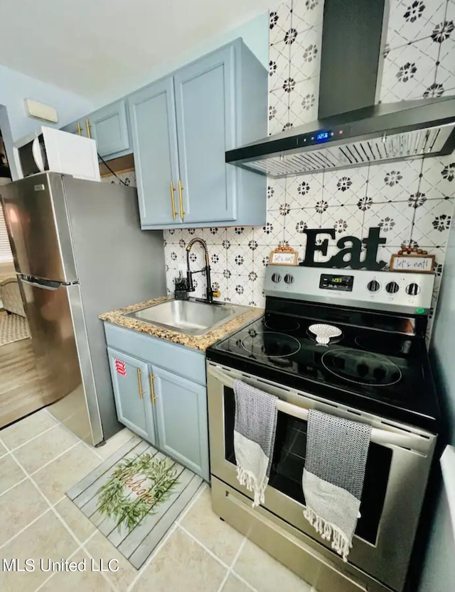 kitchen with wall chimney range hood, tasteful backsplash, light tile patterned floors, appliances with stainless steel finishes, and sink