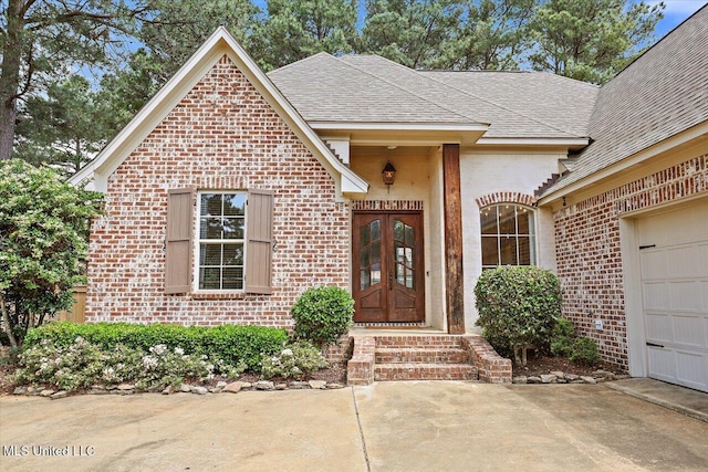 doorway to property with brick siding, french doors, a shingled roof, and a garage