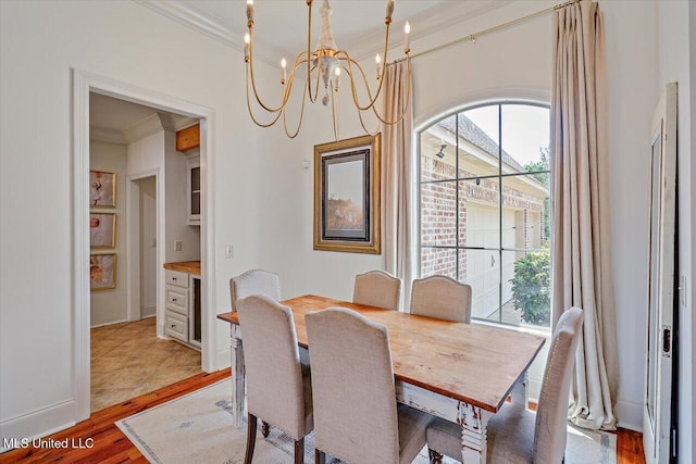 dining area with crown molding, a notable chandelier, a healthy amount of sunlight, and light wood finished floors