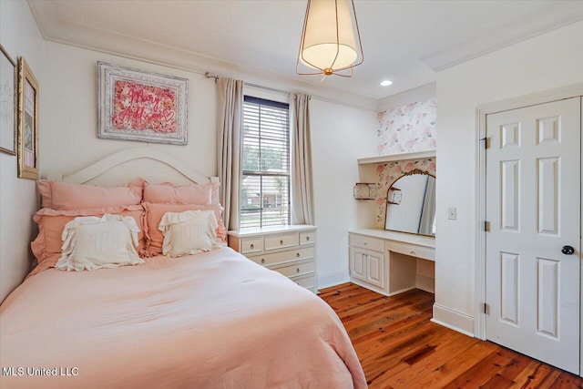 bedroom with recessed lighting, built in desk, and light wood-style flooring