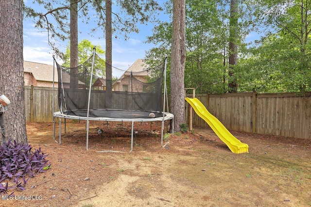 view of yard with a fenced backyard, a trampoline, and a playground