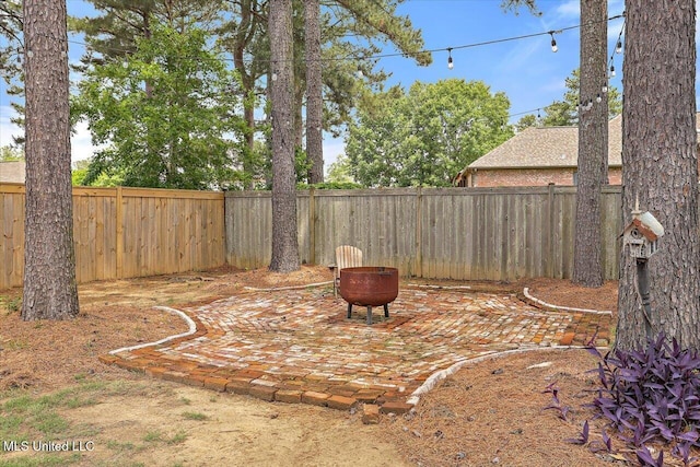 view of yard featuring a patio, a fenced backyard, and a fire pit